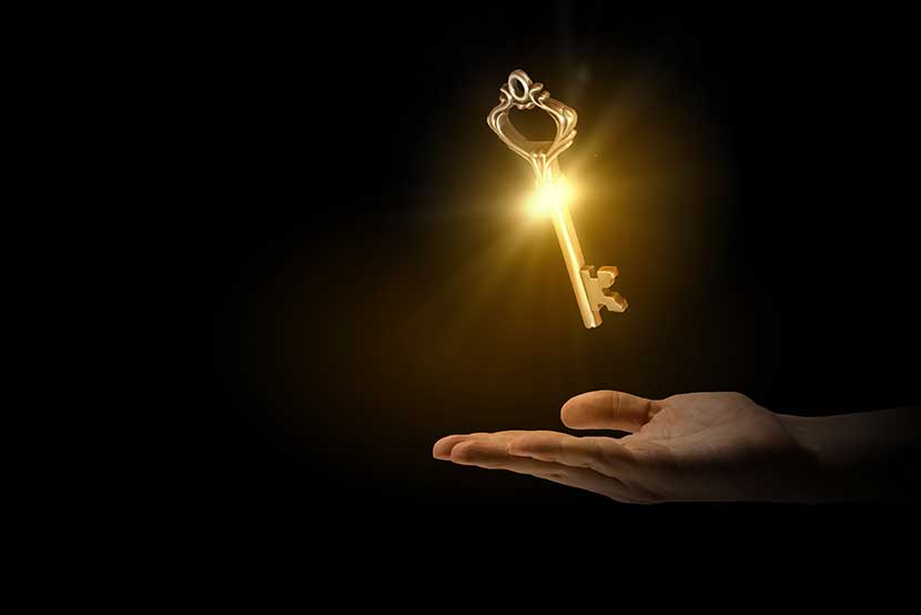 Shining golden key hovering above a hand