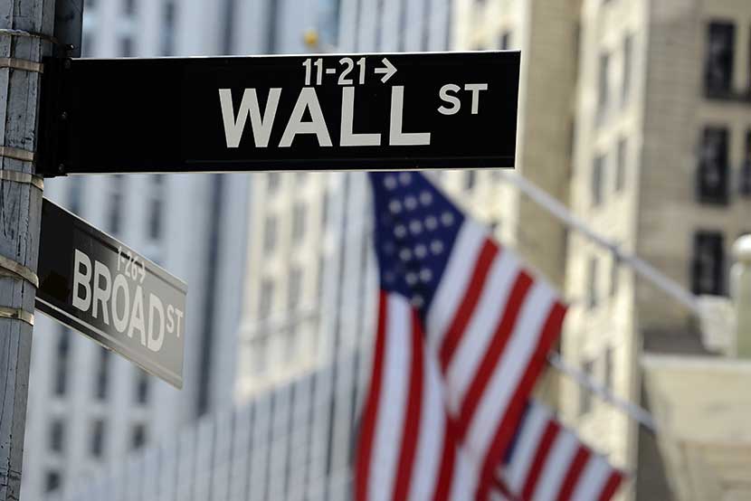 The corner of Wall Street and Broad Street in New York with U.S. flags waving in the background
