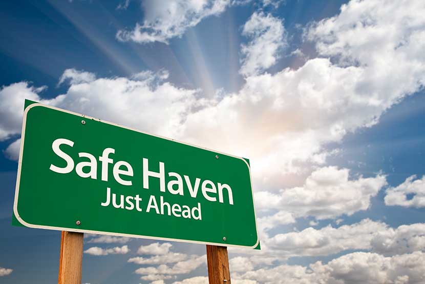 Green safe haven sign with sun breaking through clouds in the background