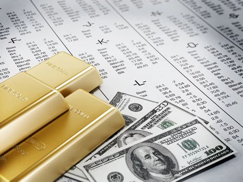 Bars of gold and three stacks of $100 and $50 bills atop an alphabetized list of stocks