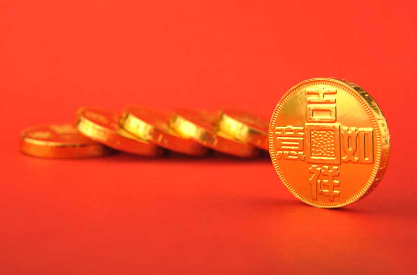 Fallen stack of Chinese gold coins against bright red backdrop
