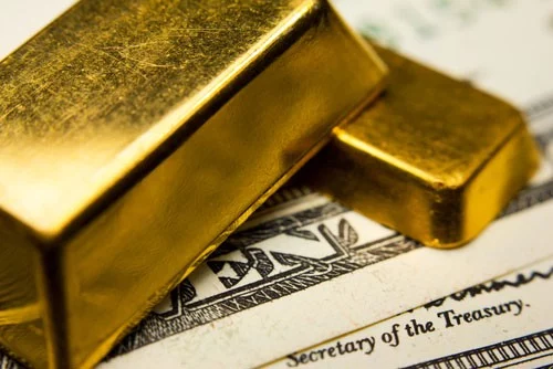 One large gold bar and one small gold bar atop crisp United States dollar bills