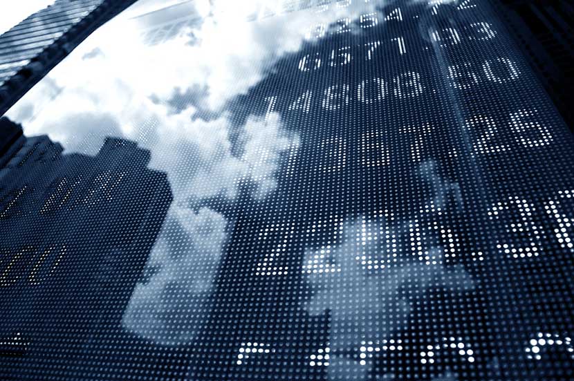 The reflection of clouds and city buildings on digitally displayed stock market prices