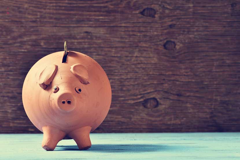 Coin going into terra cotta piggy bank