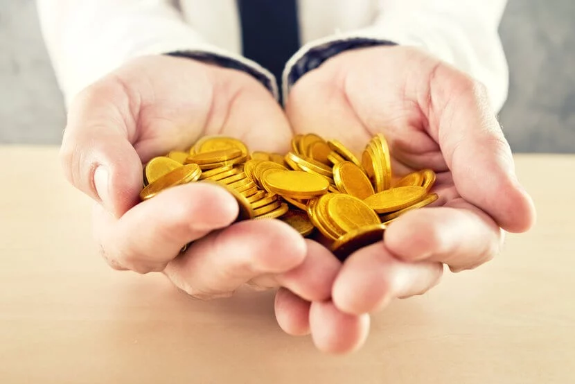 Man dressed in business attire holding gold coins, wondering whether to buy gold locally or buy gold online