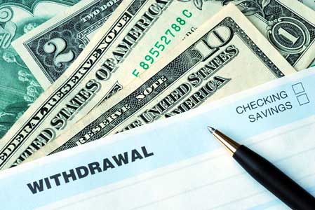 Withdrawal slip and various denominations of cash, as customer withdraws cash from bank