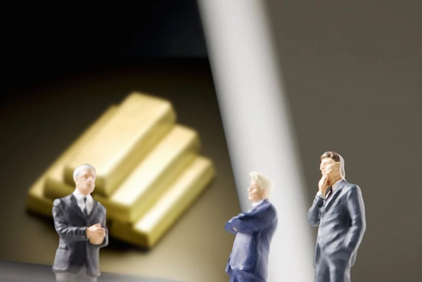 Politician figurines in front of gold bars, discussing future of gold