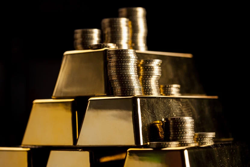 Stack of gold bars with gold coins on top