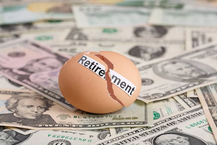 Broken egg that says, "Retirement" on top of U.S. dollar bills