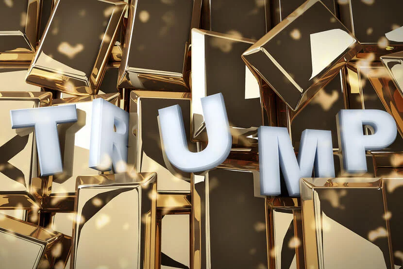 Silver letters spelling "Trump" against background of gold bars