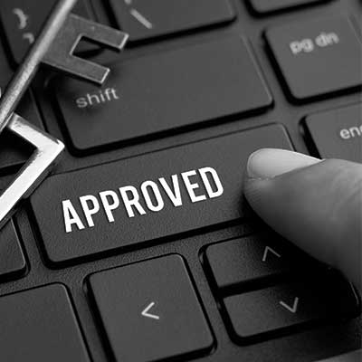 Black and white image of a finger pressing "approved" key on a keyboard