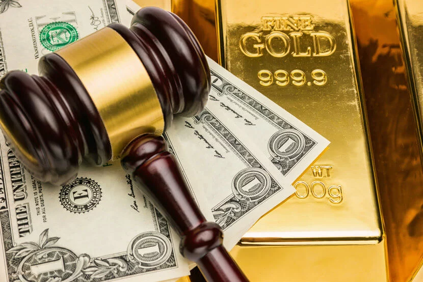 Courtroom gavel, U.S. dollar bills, and shiny gold bars