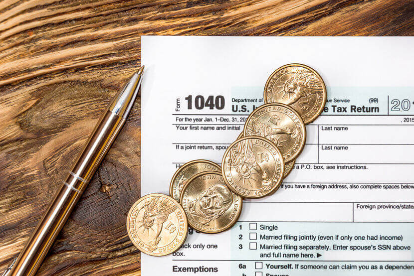 1040 tax form and gold coins on wooden table