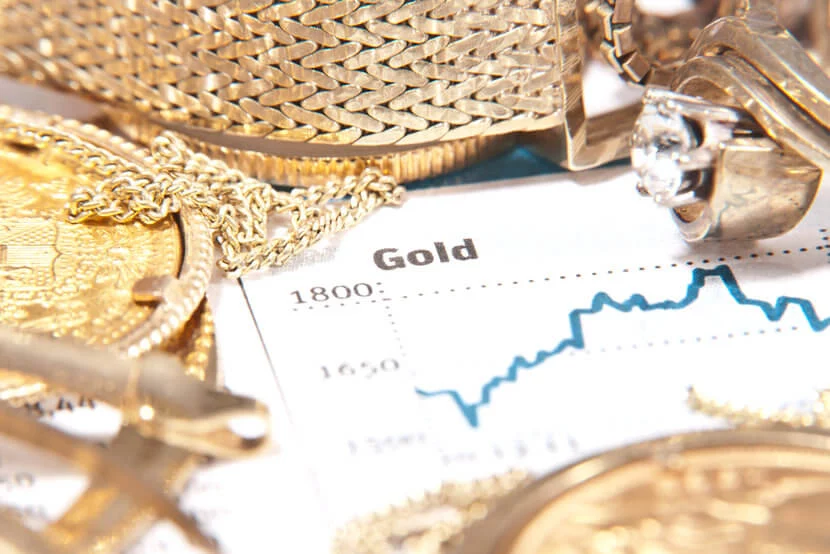 Gold chart surrounded by gold coins and jewelry