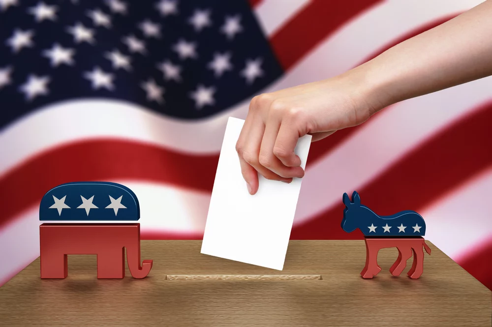 Hand with ballot and wooden box on Flag of USA