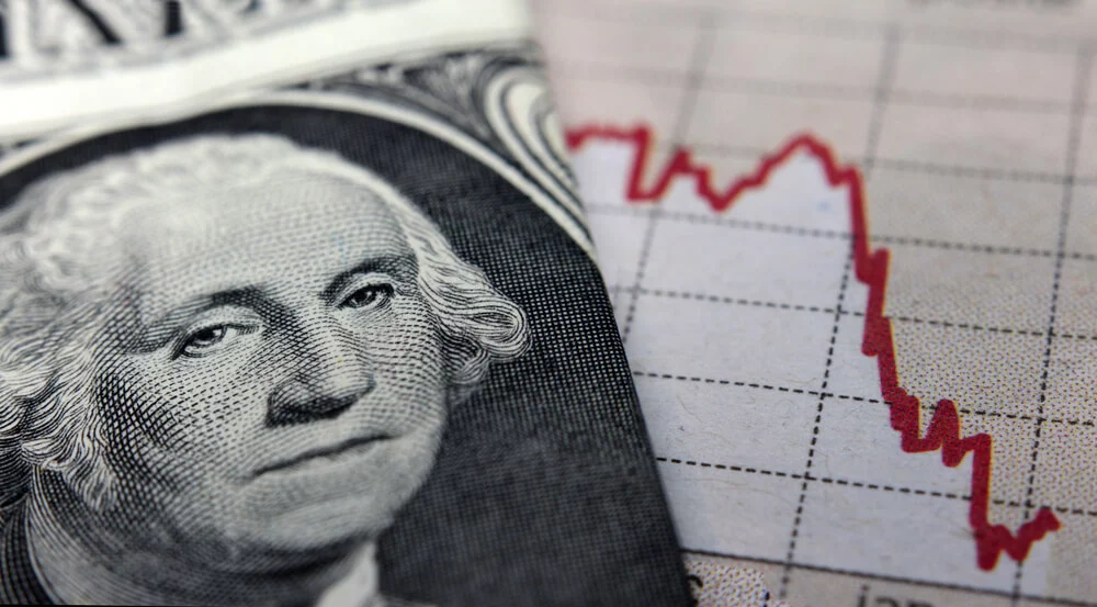Dollar bill sitting on top of arrow graph showing downward trend