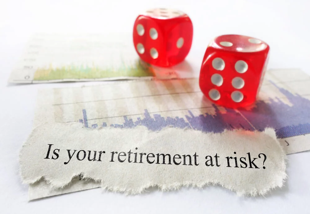 Is your retirement at risk? on ripped piece of paper sitting on graphs with red dice in foreground