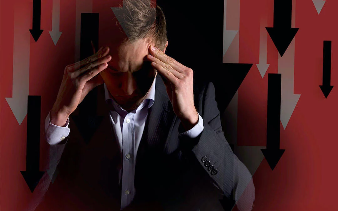 EconomicHangover-light-1 Businessman with serious look and hands on head in front of downwards trends