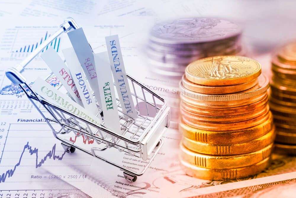 Commodities, stocks, bonds, ETFs, REITs, and mutual funds in a shopping cart, surrounded by gold and silver coins sitting on top of financial charts and graphs