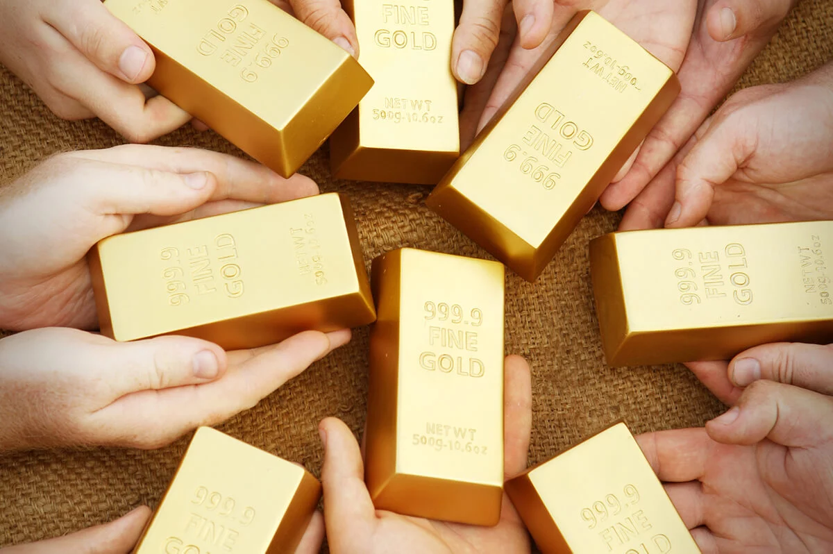 Multiple Hands Holding Gold Bars