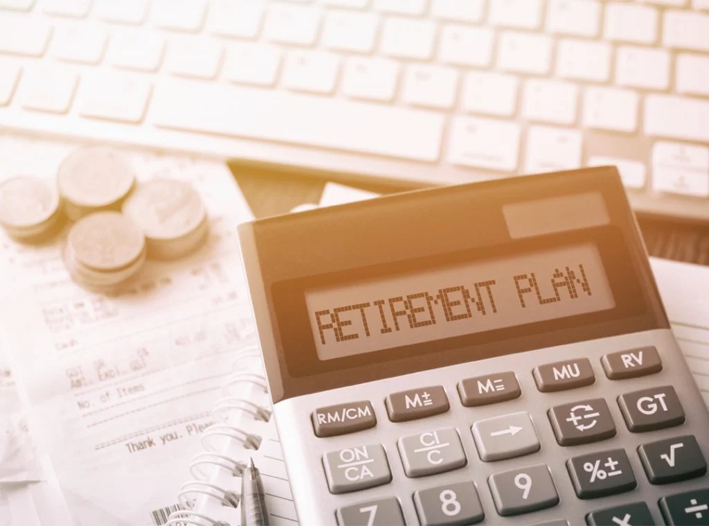 Retirement plan in the readout screen of a calculator with receipts, coins and computer keyboard in background