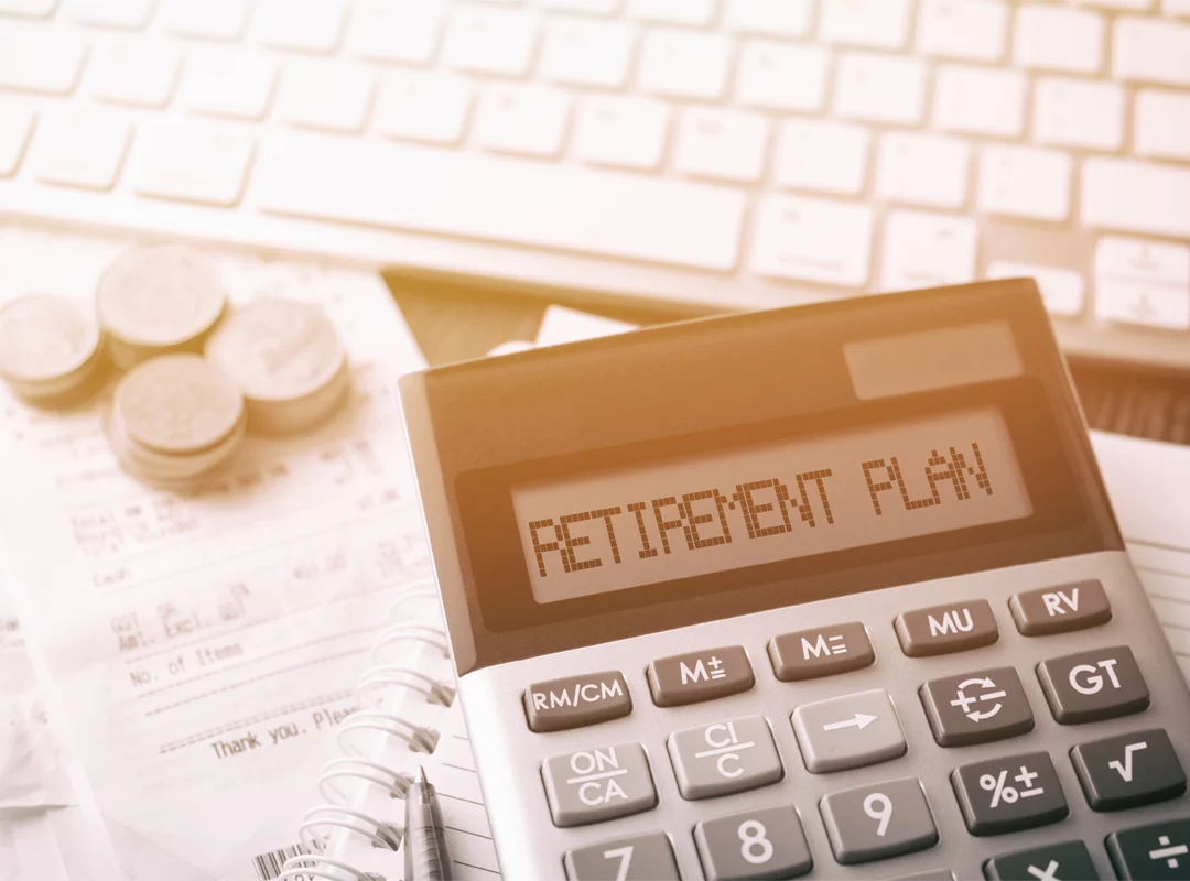 Retirement Plan Calculator Retirement plan in the readout screen of a calculator with receipts, coins and computer keyboard in background
