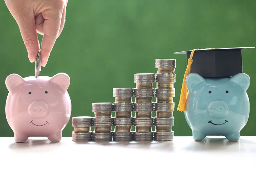 Hand putting coins into pink piggy bank on the left, various stacks of coins in the middle, and a turquoise piggy bank on the rightrepresenting education fund