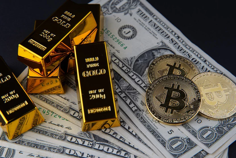 how-gold-stacks-up-against-other-assets_blog Gold bars and bitcoins sitting on top of dollars