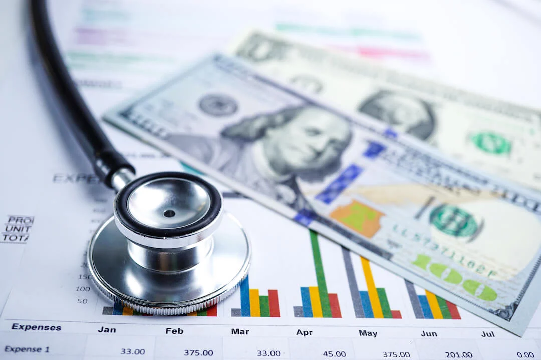 Stethoscope and U.S. dollars on charts and research data