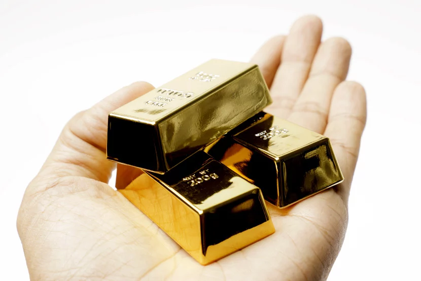 Hand holding three gold bars