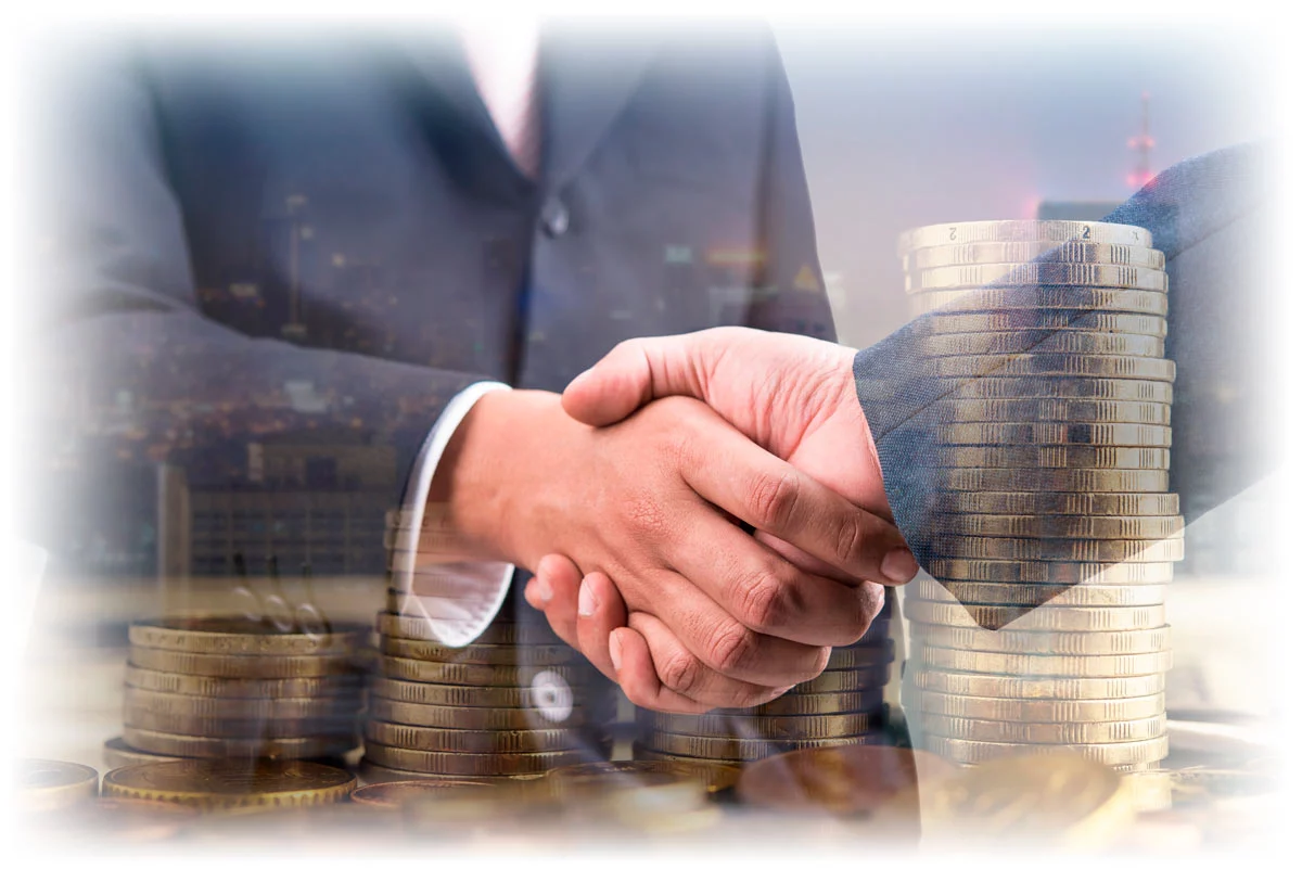 Business people shaking hands over image of stacks of gold coins Business people shaking hands over image of stacks of gold coins