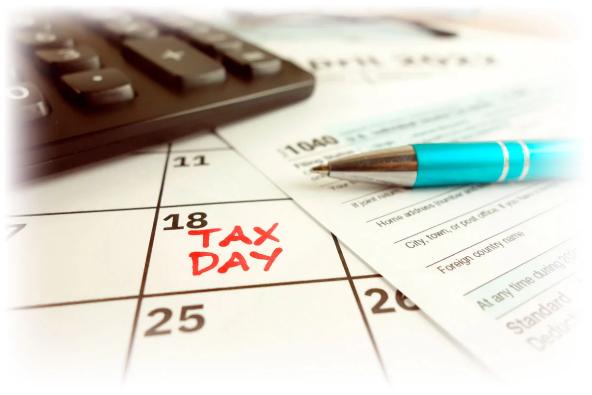 Calendar marking April 18 as Tax Day along with calculator and 1040 tax form Calendar marking April 18 as Tax Day along with calculator and 1040 tax form