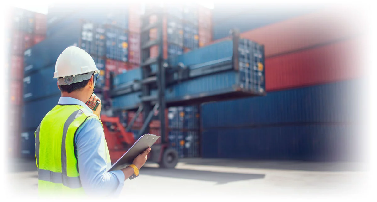 Worker looking on as forklift moves shipping container