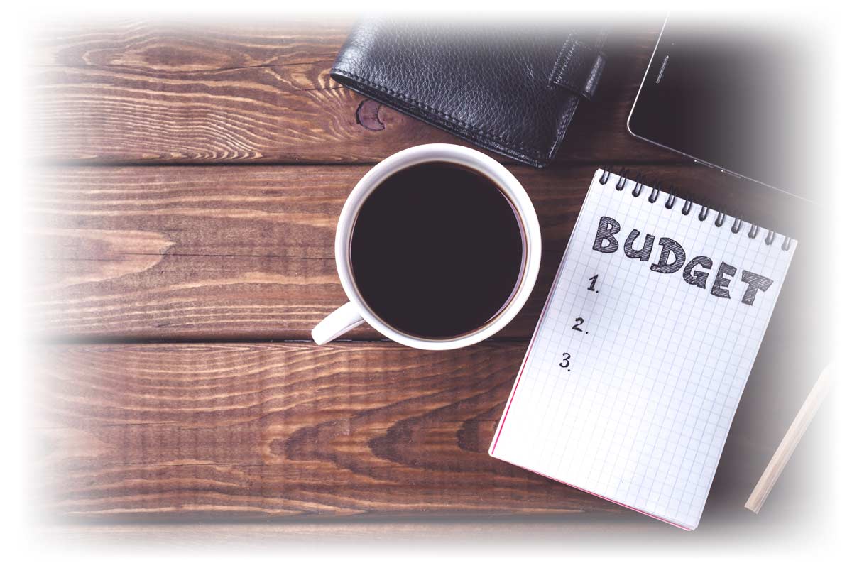Coffee, phone and notebook open to a page labeled “BUDGET”
