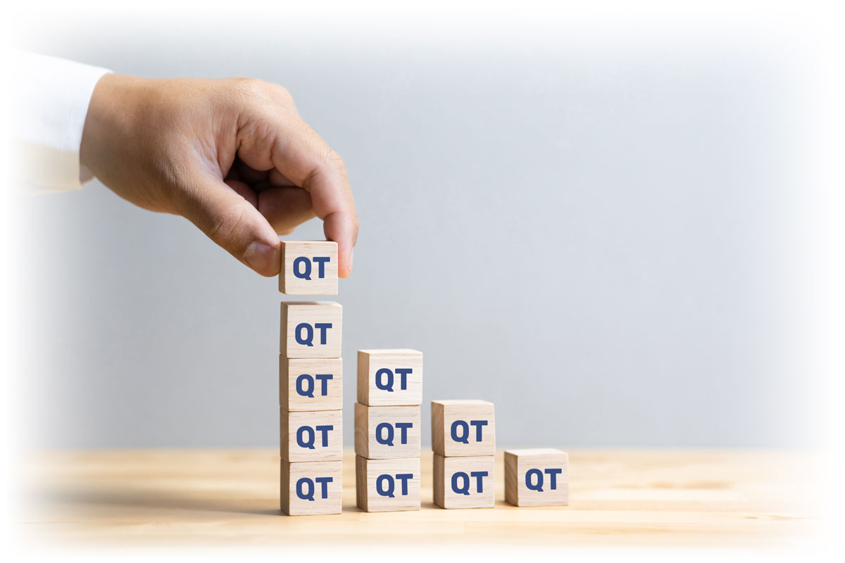 Hand placing “QT” letter block on progressively smaller stacks of letter blocks