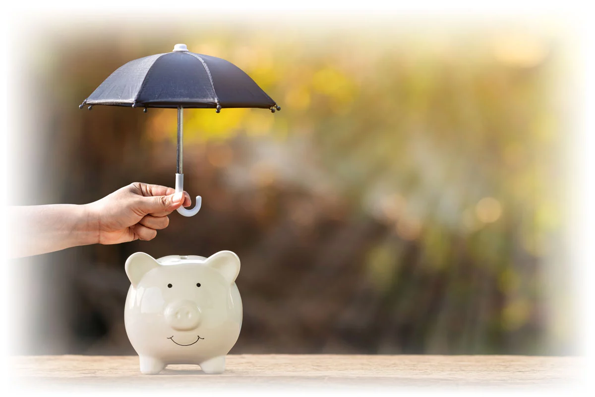 Hand holding umbrella over piggy bank