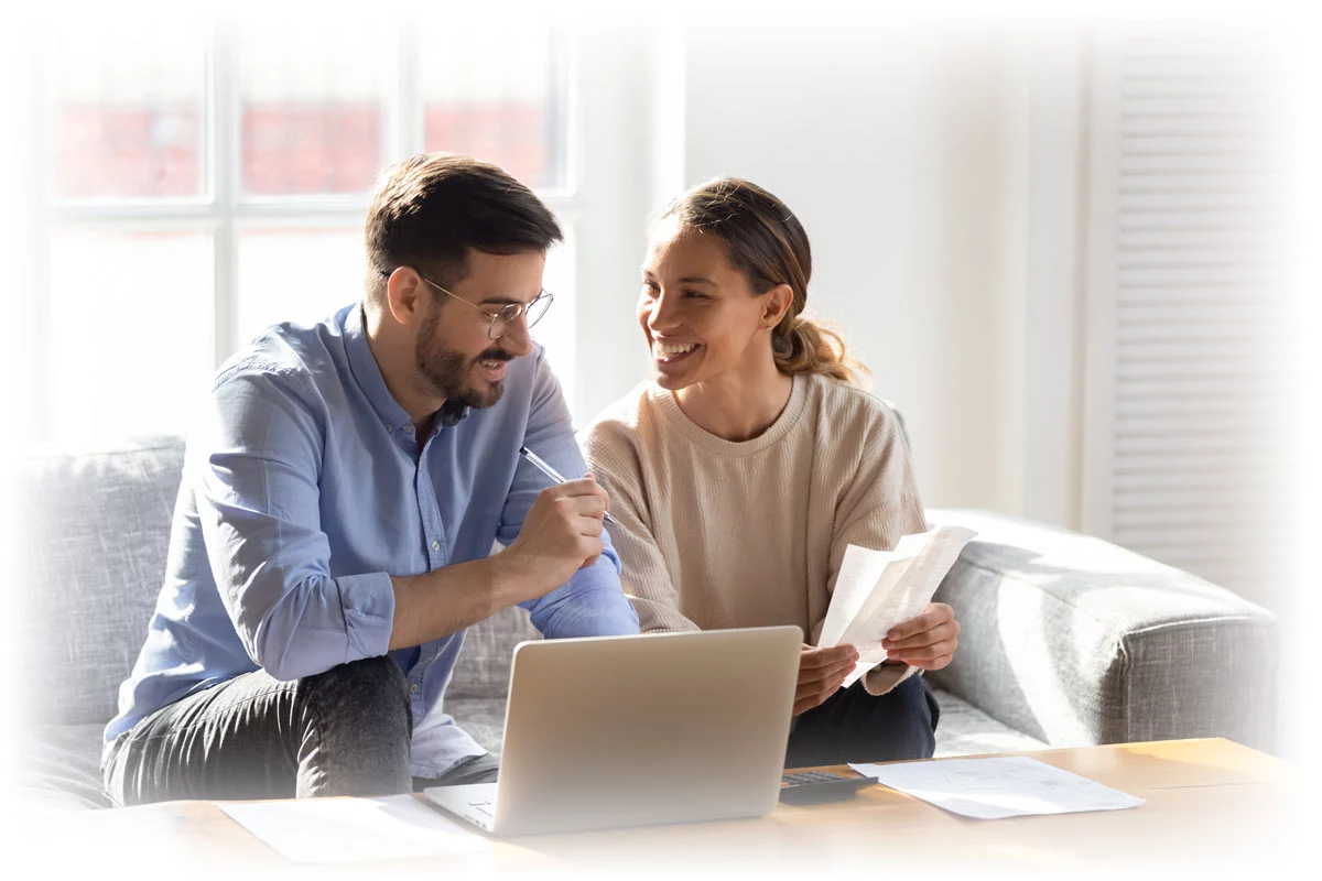 Couple happily working on laptop with receipts and other paperwork