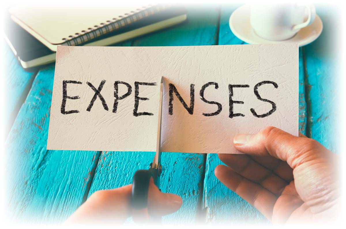 Hands using scissors to cut paper reading “EXPENSES” in half