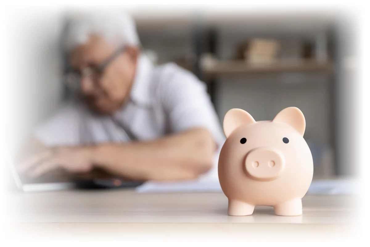 Man working on laptop with piggy bank in foreground