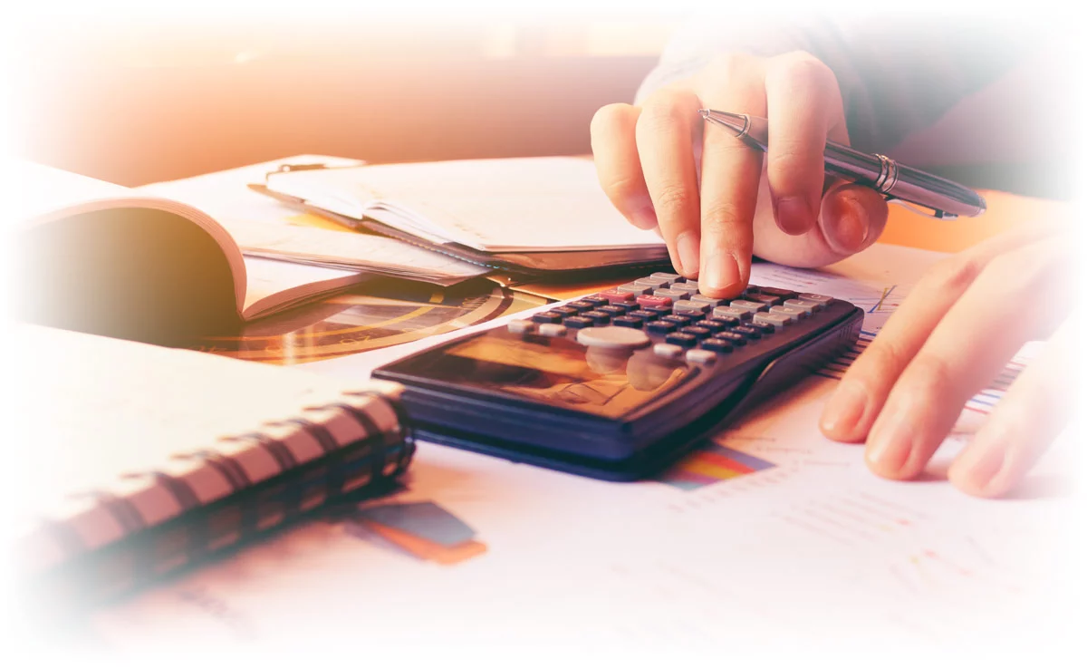 Hands working calculator on table covered in financial papers
