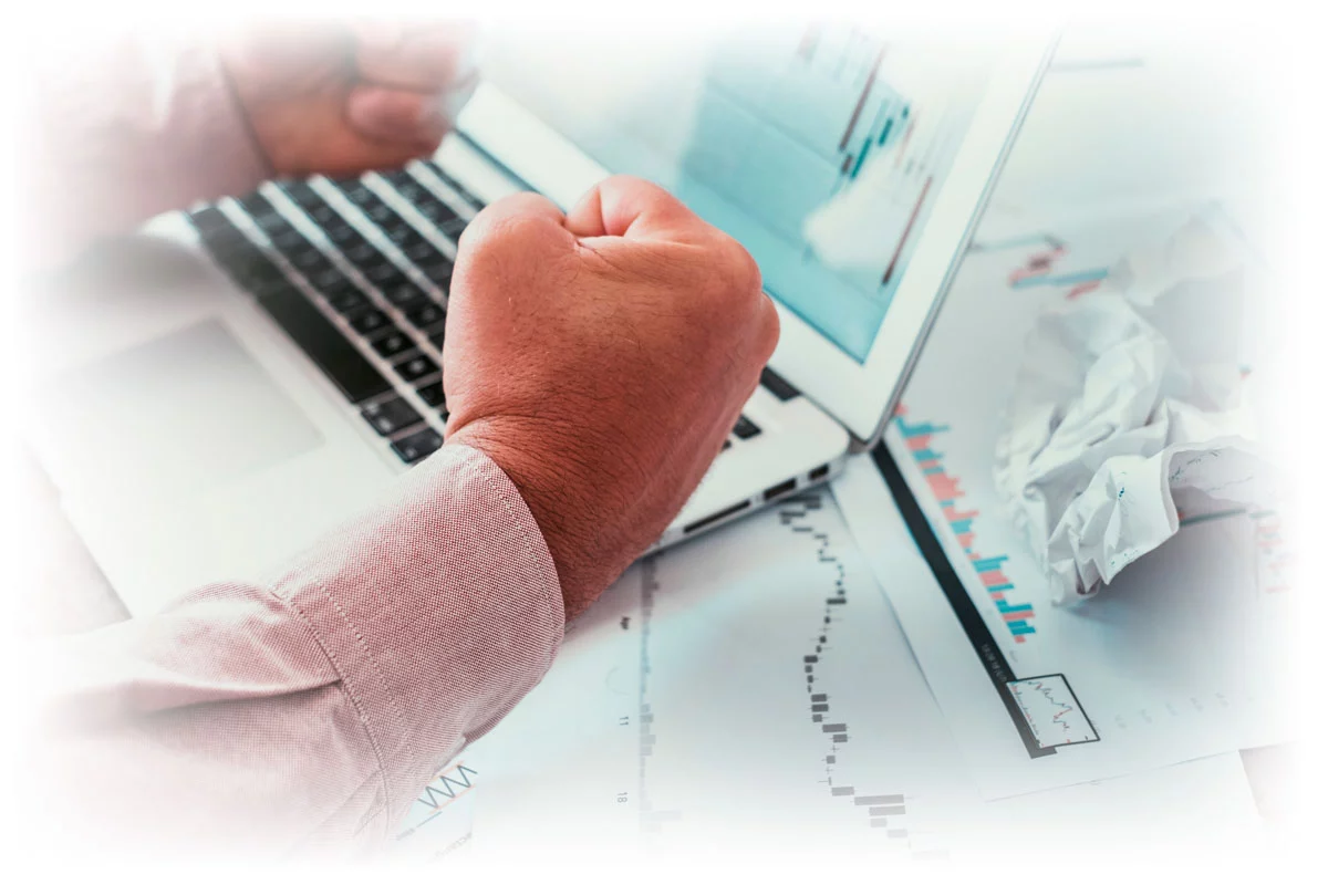 Hands making fists in frustration while looking at stock charts