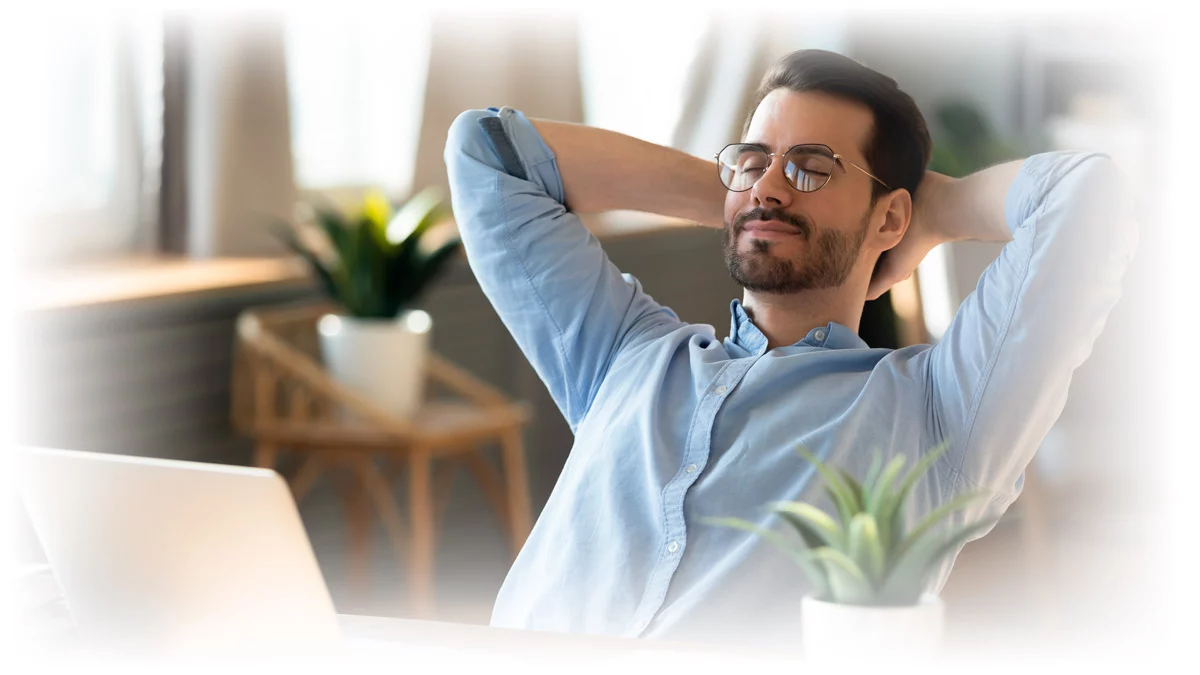 Man leaning back from laptop with arms behind head