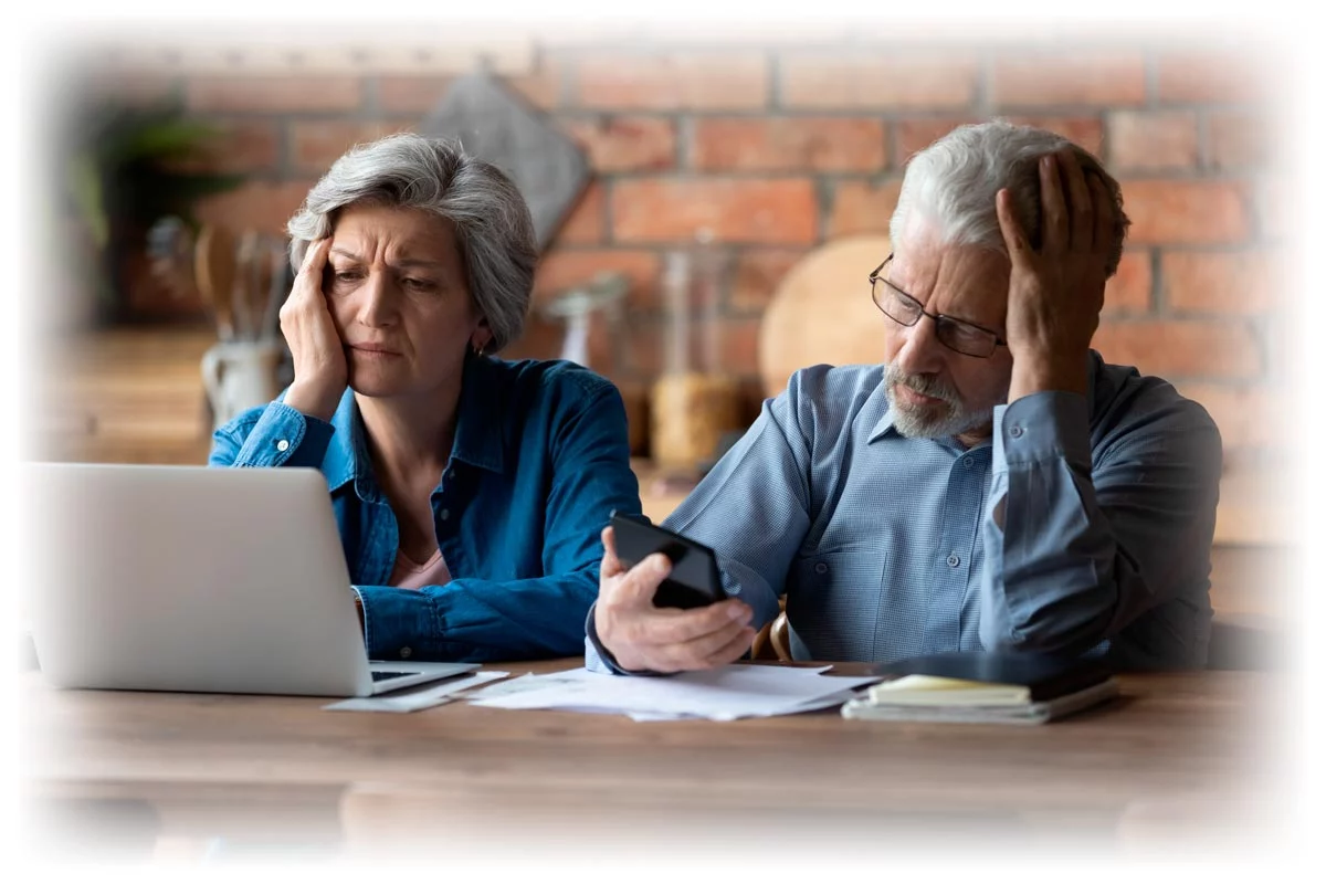 Concerned-retired-couple_1200px Concerned retired couple looking at laptop, phone, and financial documents