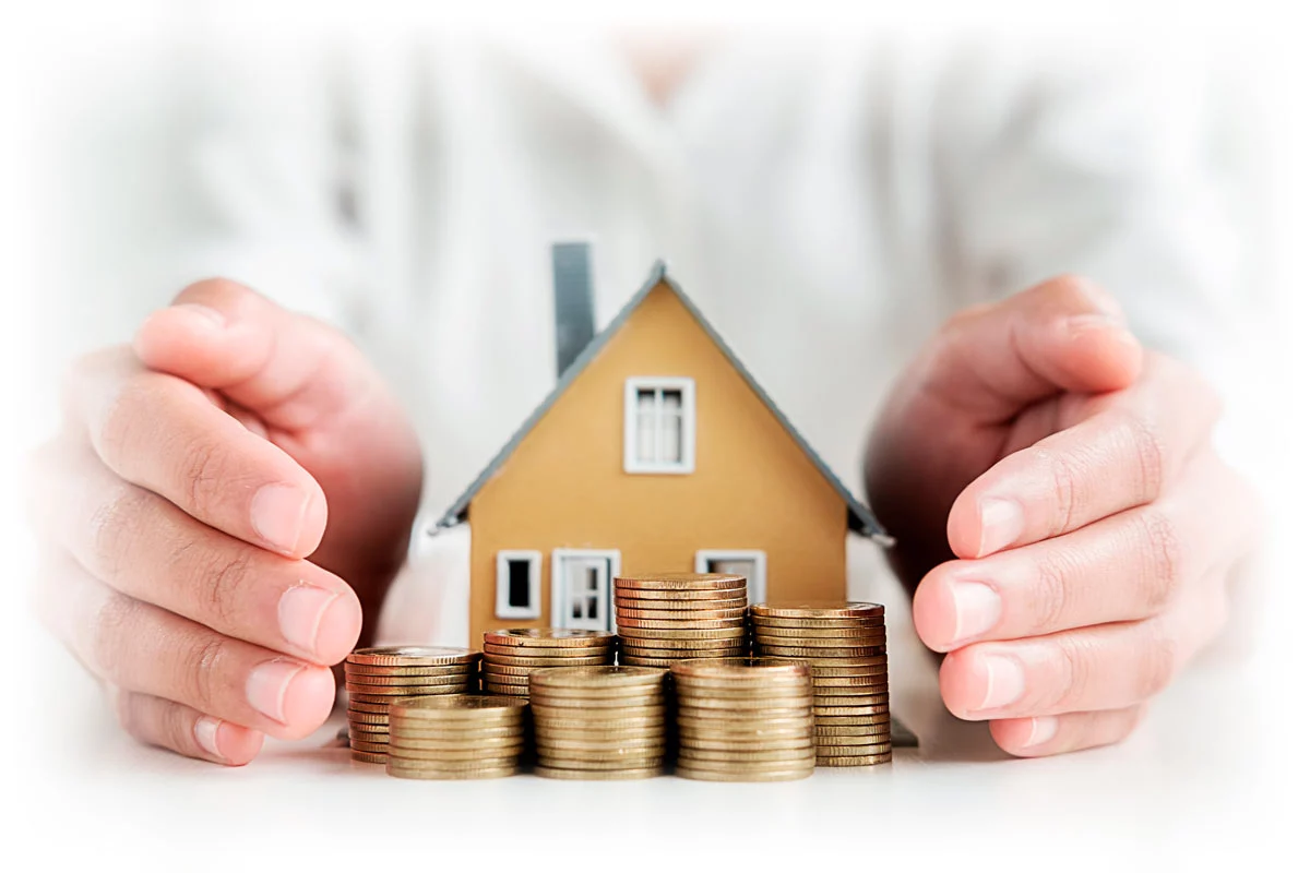 Hands surrounding paper house and stacks of gold coins
