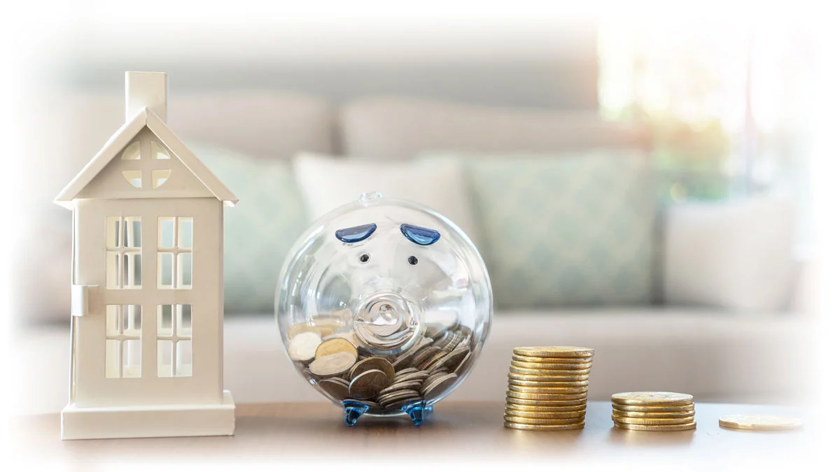 Paper house, clear piggy bank filled with coins, and stacks of gold coins