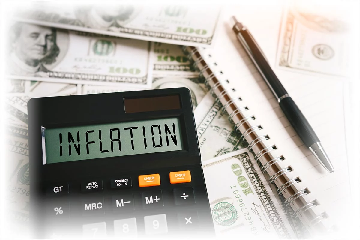 Word "INFLATION" on calculator, pen and notebook, $100 notes