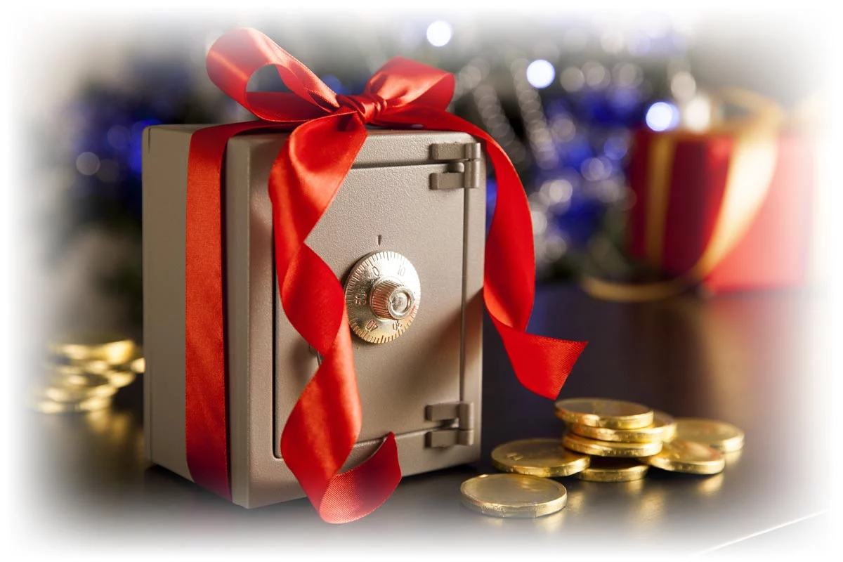 Small safe decorated with red ribbon next to small pile of gold coins