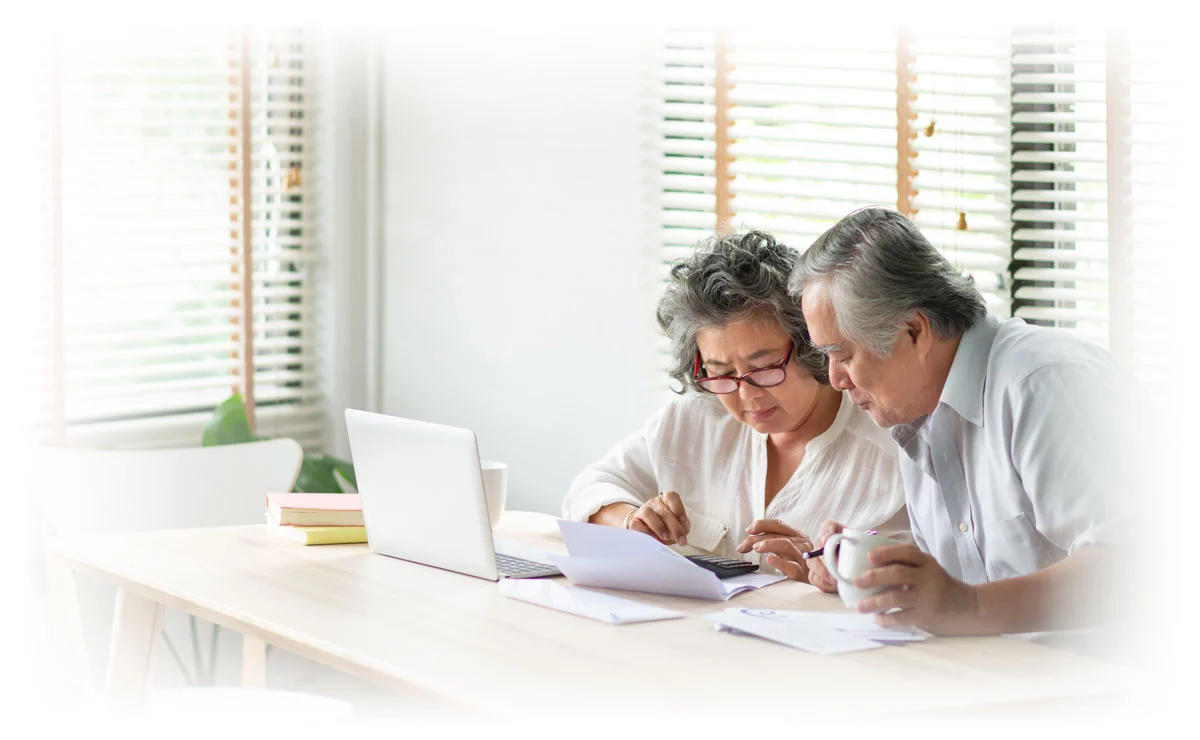 Seniors looking over financial documents with laptop and calculator