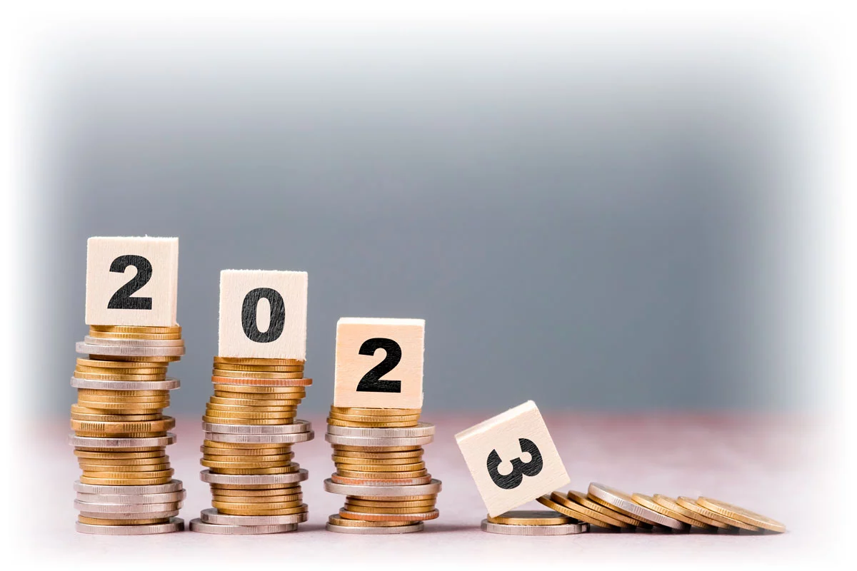 Woods blocks reading "2023" on stacks of coins, with stack under "3" toppled over