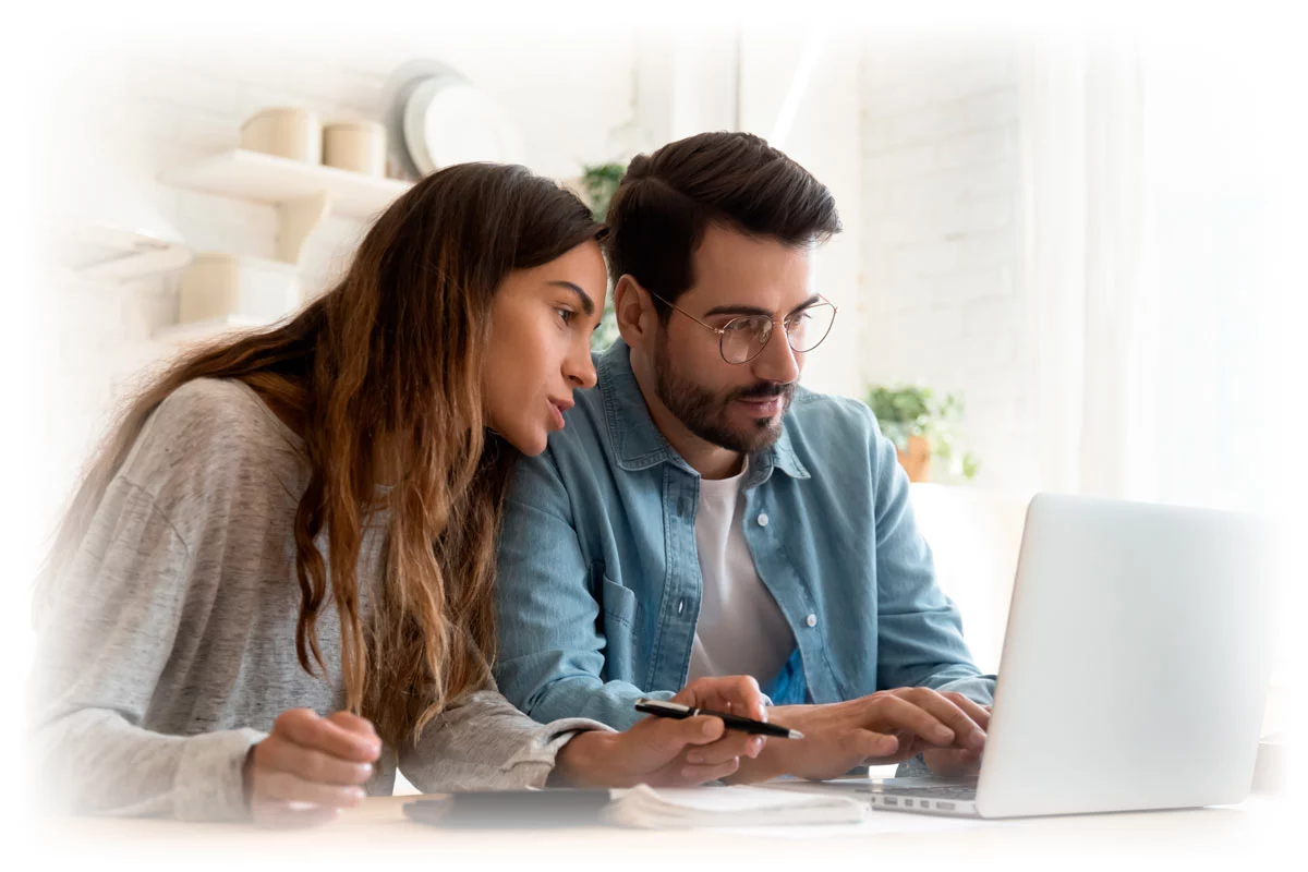 Couple with notebook and pen focusing on laptop
